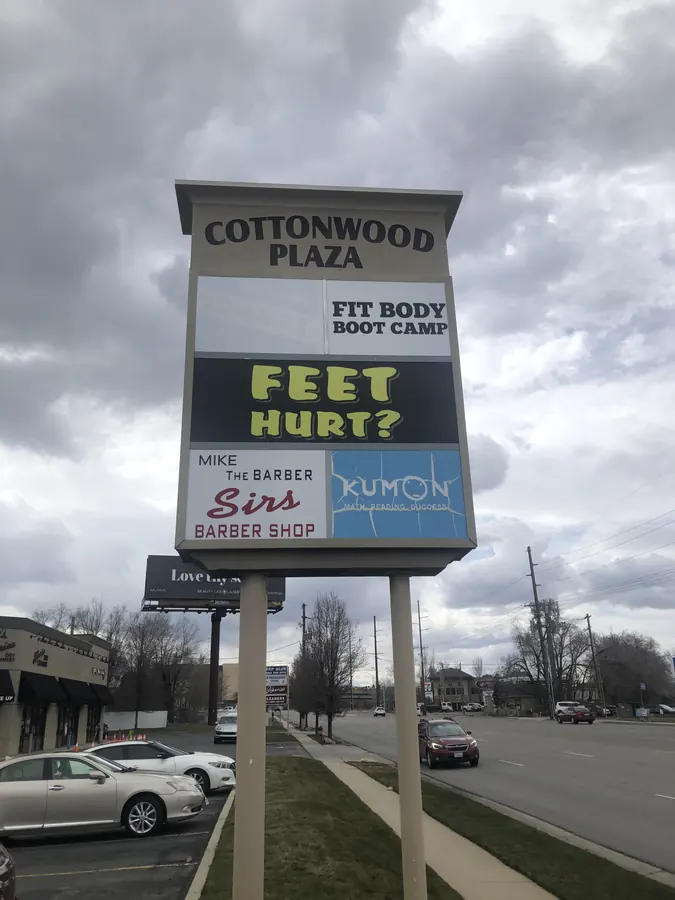 The Cottonwood Plaza street sign listing Mike the Barber, Sirs Barber Shop