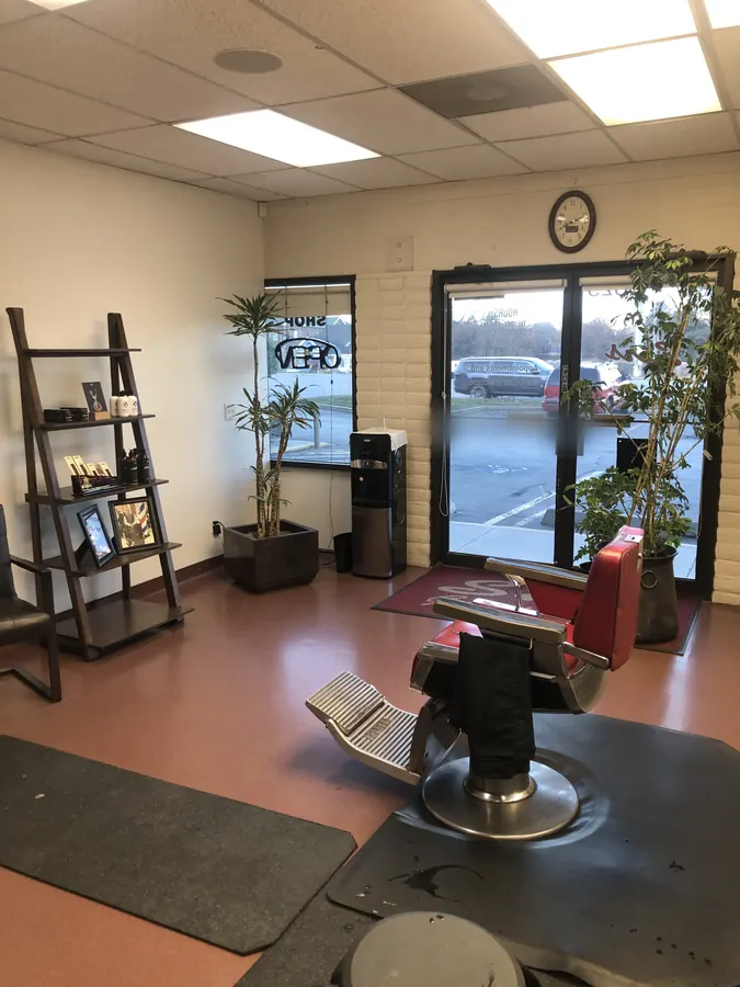 A red barber chair facing the front windows inside Sirs Barbershop